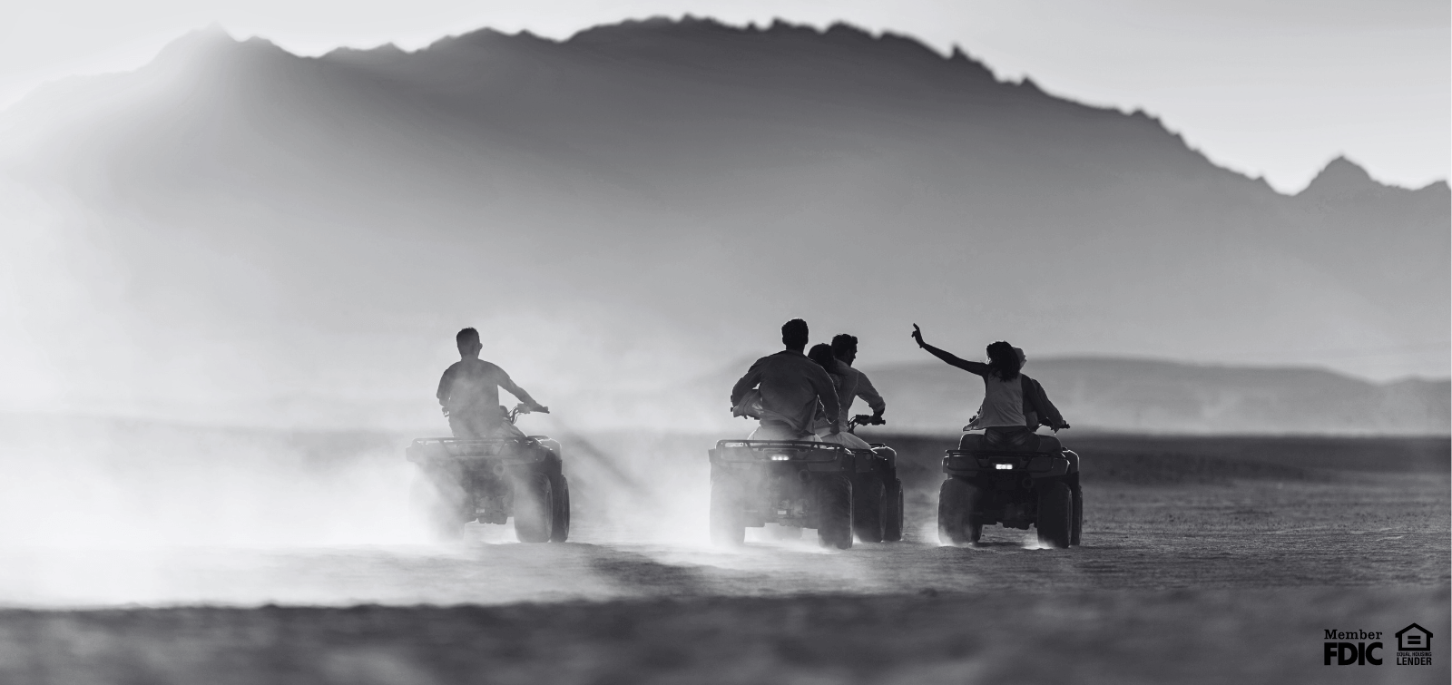 a group of friends ride four wheelers through the dessert.