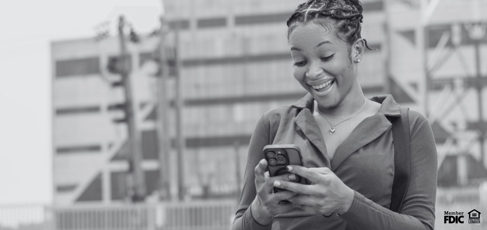 A young woman smiles while looking at her mobile banking app and seeing how much she's saved.