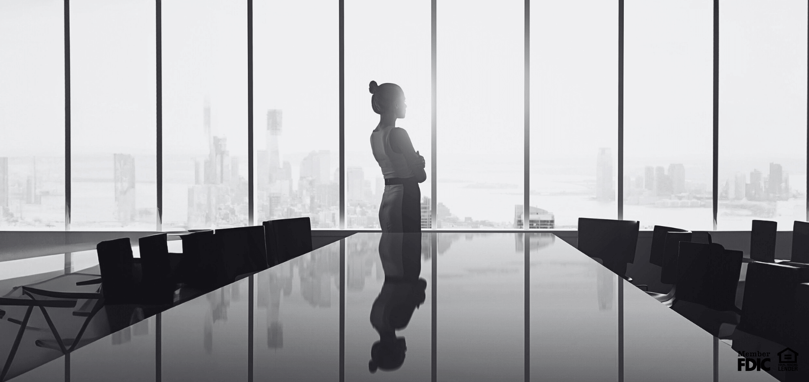 a lone woman stands silhouetted by light in an empty board room