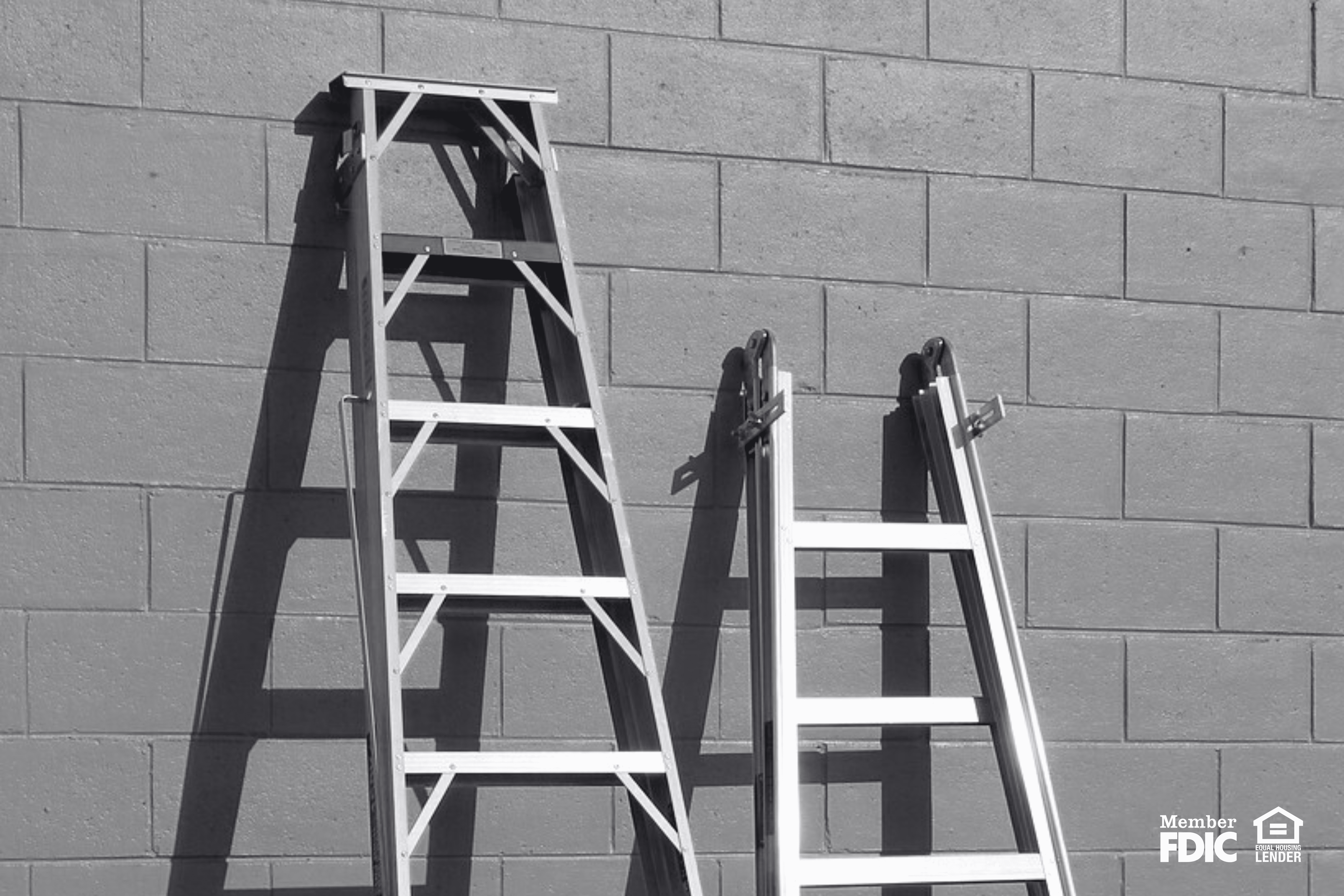 two ladders lean up against a wall