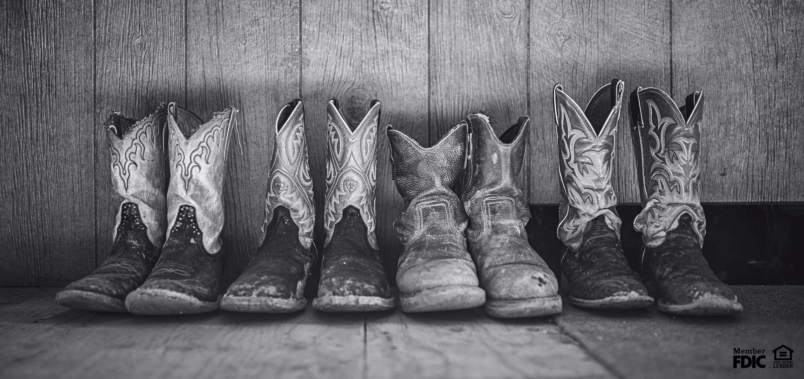 four pairs of cowboy and cowgirl boots lined up against the wall.