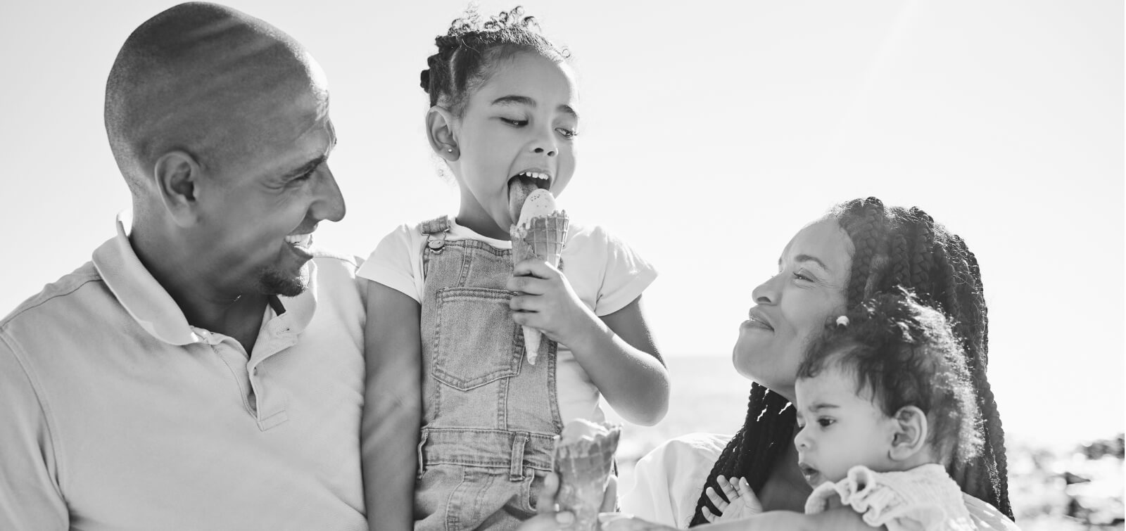 Family outside together smiling while their daughter eats ice cream
