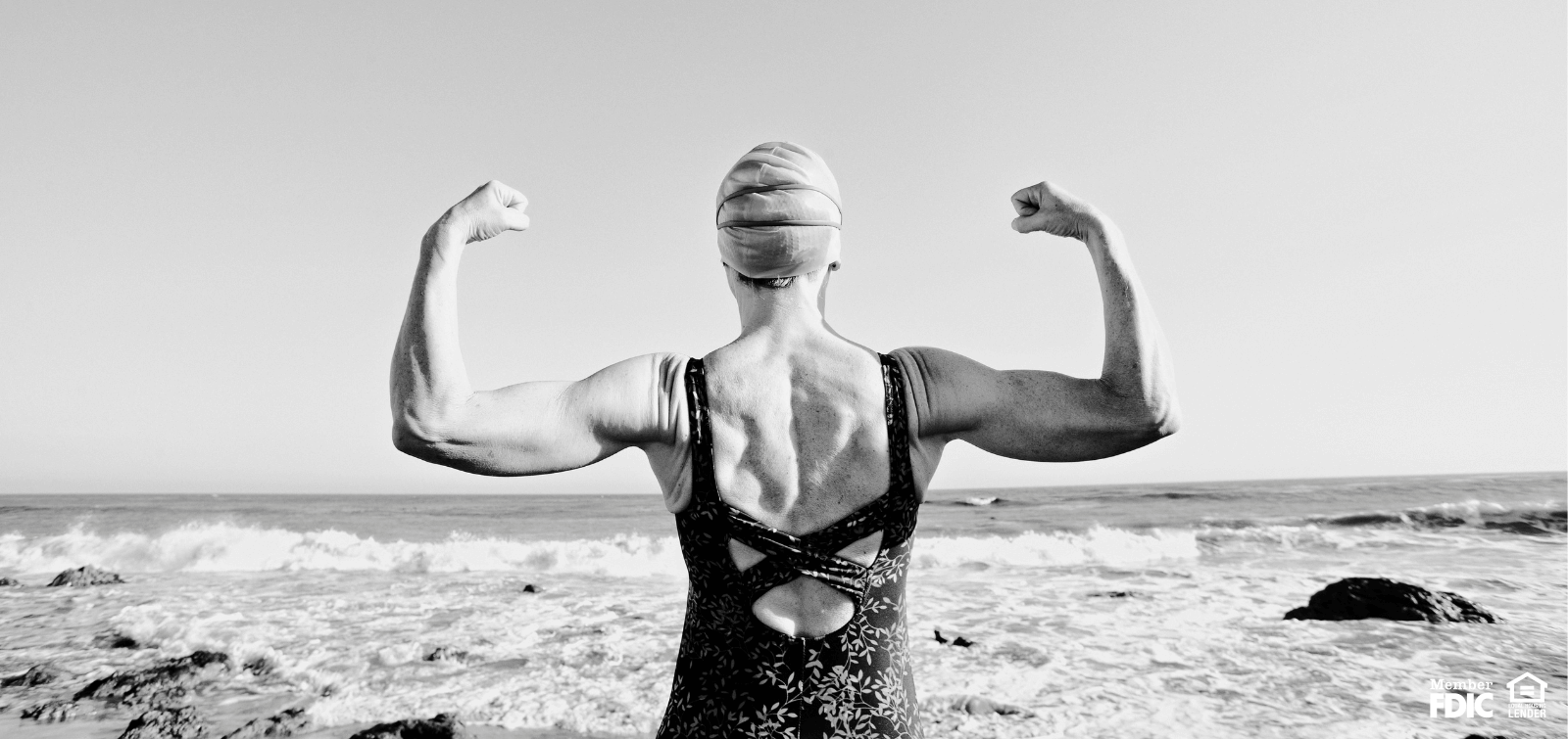 A female swimmer flexing in front of the ocean.