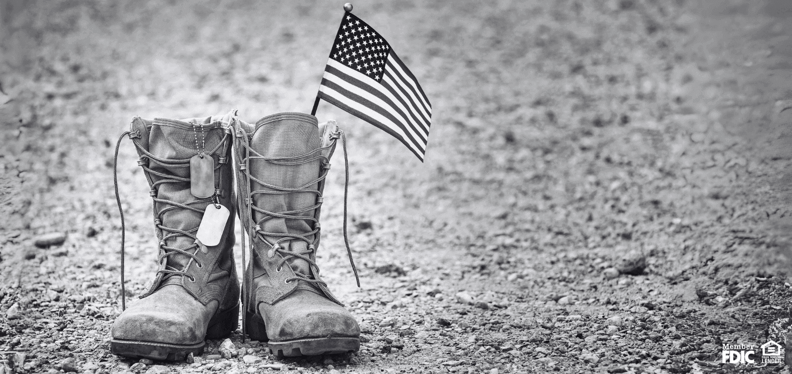 a pair of regulation military boots sit on the ground with a American Flag flying from them.